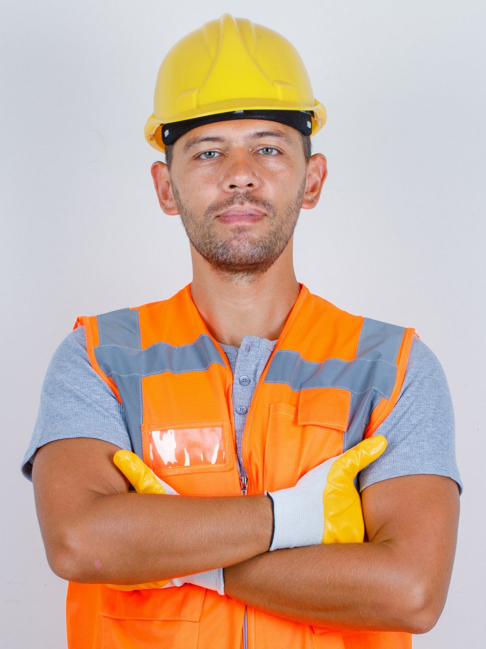 Male builder in uniform standing with crossed arms and looking confident , front view.
